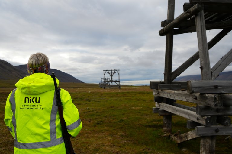 During fieldwork in Svalbard, the danger of polar bears is real. When serving as polar bear guard, researcher Anne-Cathrine Flyen must remain active and alert. Here by the cableway pylons in Adventdalen, from Mine 6 to Longyearbyen. Photo: Brita Flyen Bolin