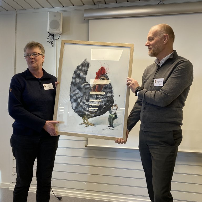 Leder ved genbanken for verpehøns på Hvam, Mette Nafstad Bjerkestrand, ble hedret med en karikaturtegning av Hilde Thomsen fra institusjonene og organisasjonene i genbankens styringsgruppe og faggruppe. Ekspedisjonssjef Pål Vidar Sollie fra LMD overrakte gaven på genbankens 50-årsmarkering tidligere denne uka.  Foto: Linn Borgen Nilsen