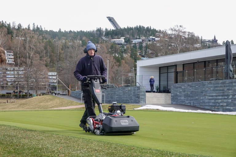 Første klipping av treningsgreenen ved Oslo Golfklubb fredag 30.april. Snøen ligger fortsatt i åsen opp mot Holmenkollen. Foto: Morten Günther