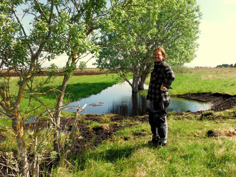 NIBIO-forsker Simon Weldon ved restaurert myr. Restaurering av myr innebærer å tilbakeføre menneskepåvirket myr til naturlig tilstand gjennom tiltetting av grøfter, heving av grunnvannstanden og gjeninnføring av myrvegetasjon. Foto: Hlynur Oskarsson